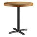 A Lancaster Table & Seating round wooden table with a black base.