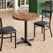 A Lancaster Table & Seating round wood table with wine glasses on it.