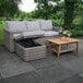 An Outdoor Interiors wicker sectional with a coffee table and two pillows on a patio.