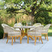 An Outdoor Interiors teak and nautical rope dining chair with a Sunbrella cushion next to a table on an outdoor patio.