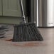 A Lavex black unflagged angled broom head sweeping a floor.