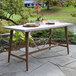 An Outdoor Interiors eucalyptus counter height table with a tray on it on a stone patio.