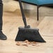 A person sweeping the floor with a Lavex black angled broom head.