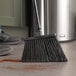A black Lavex broom head sweeping the floor.