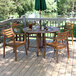 An Outdoor Interiors Eucalyptus Danish stackable arm chair on a wooden deck with a table and chairs.