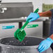 A person wearing blue gloves scrubbing with a green Lavex brush.