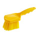 A close-up of a Lavex yellow utility brush with a handle.