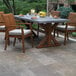 An Outdoor Interiors Eucalyptus Stackable Arm Chair with a beige cushion on a patio next to a table with a plate of fruit.