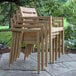 A stack of Outdoor Interiors Antique Wash Eucalyptus dining chairs on a stone patio.