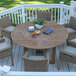 An Outdoor Interiors round eucalyptus table with chairs on a wooden deck.