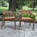 Two Outdoor Interiors Eucalyptus Stackable Dining Chairs on a stone patio.