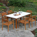 An Outdoor Interiors Eucalyptus wooden chair on a stone patio next to a table with wine glasses and cheese.