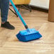 A person using a Lavex blue bi-level floor scrub brush to clean a floor.