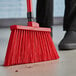 A red broom sweeping the floor.