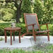 An Outdoor Interiors wicker and eucalyptus lounger on a patio with a table and a glass on it.