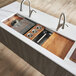 A Ruvati stainless steel workstation sink with wood tray and cutting board accessories.