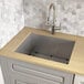 A Ruvati stainless steel undermount laundry sink in a kitchen.