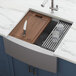 A Ruvati Verona farmhouse kitchen sink with a knife and cutting board inside.