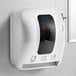 A white Lavex lever-activated paper towel dispenser on a tile wall.