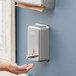 A hand using a Lavex stainless steel surface mounted liquid soap dispenser.