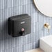 A black Lavex stainless steel manual liquid soap dispenser on a tile wall.