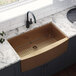 A Ruvati Terraza farmhouse sink with a copper finish in a kitchen with a metal rack in it.