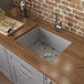 A Ruvati stainless steel rectangular undermount bathroom sink on a wooden counter.