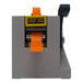 A Tach-It Manual Definite Length Tape Dispenser with an orange tape roll on a black surface.