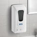 A white Lavex automatic liquid soap and sanitizer dispenser on a tile wall.