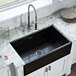 A Ruvati Fiamma glossy black farmhouse sink on a white counter.