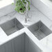 A Ruvati stainless steel double-bowl sink in a kitchen counter with a potted plant.