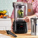 A silver AvaMix commercial blender with a black sound enclosure on a wooden counter.