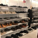 A mannequin standing in front of a white UDIZINE retail clothing display set filled with shoes.