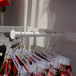 A UDIZINE white round tubing faceout holding red plaid pants on a white retail clothing rack.