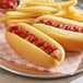 Two Martin's Famous hot dogs on sliced potato rolls with ketchup on a table in a stadium concession stand.