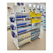 A white Udizine mobile retail clothing display stand with shelves holding white boxes with black text.