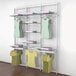 A white wall-mounted Udizine retail clothing display with clothes and dresses hanging from it.