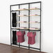 A black Udizine retail clothing display rack with clothes hanging on it.