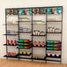 A black Udizine wall-mounted retail clothing display with shelves and sign/mirror clamps holding different colored bottles.