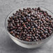 A bowl of Regal Juniper Berries on a gray surface.