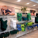 A white UDIZINE wall-mount retail clothing display with faceouts and shelves for a variety of clothing.