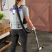 A woman using a ProTeam GoFit cordless backpack vacuum to clean a floor.
