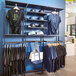 A black UDIZINE wall-mounted retail clothing display with black and blue shirts and hats on it.