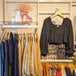 A UDIZINE black wall-mounted retail clothing display with clothes on it.