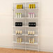 A white Udizine wall-mounted retail clothing display shelf with various products on it.