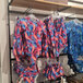 A black UDIZINE retail clothing display with swimsuits and other clothing hanging on 12 rails.