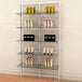 A white Udizine wall-mounted retail clothing display with shelves holding different products.