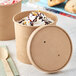 Two Choice kraft paper food cups filled with ice cream on a table.