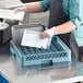 A person holding a white plate puts it into a Main Street Equipment all purpose peg rack.