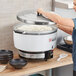 A woman using an Emperor's Select gas rice cooker to prepare rice.